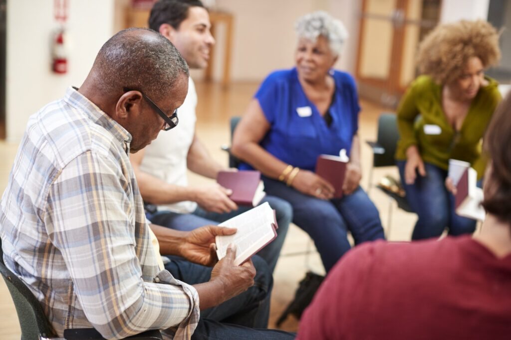 A diverse group of people sit in a circle, each holding a book, engaged in lively discussion about the latest park activities. The bright room buzzes with excitement as they share insights and experiences from their latest outdoor adventures.