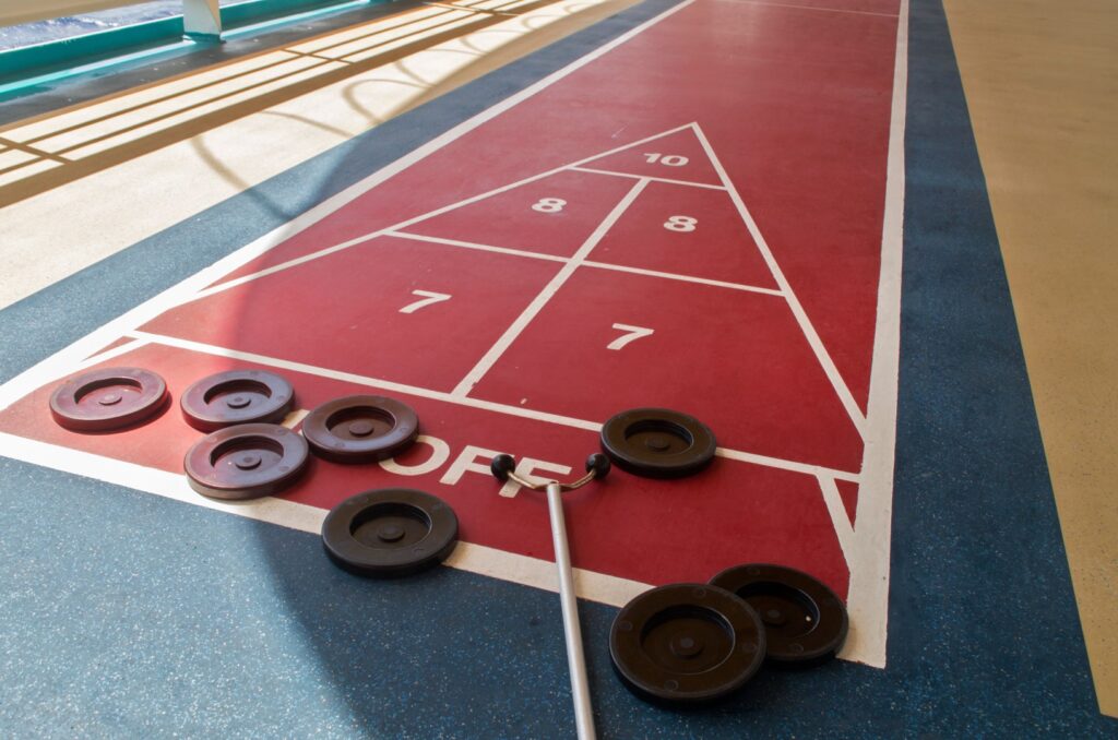 An outdoor shuffleboard court sits at the heart of our lakeside ranch activities, complete with discs and a cue placed on the "Off" area.